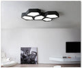Geometric shaped iron LED light with black frame and remote control on a table.