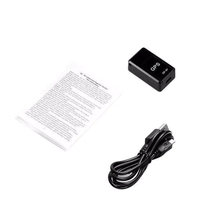 Small black magnetic GPS tracker device next to a USB charging cable on a table.