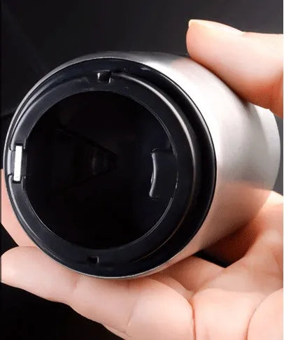 Stainless steel automatic bottle opener on a table, showing its compact size and press-down design.