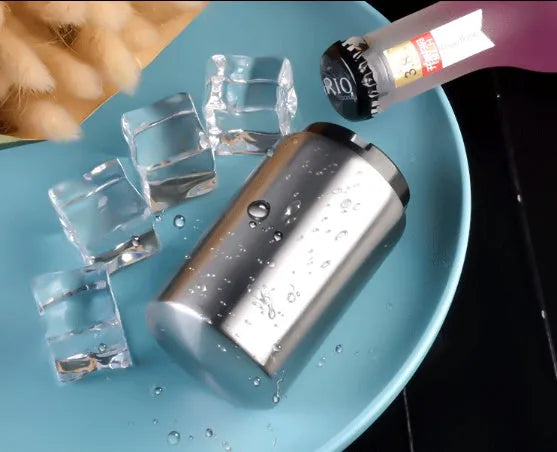 Stainless steel automatic bottle opener on a table, showing its compact size and press-down design.