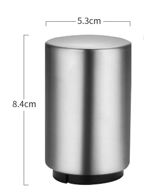 Stainless steel automatic bottle opener on a table, showing its compact size and press-down design.