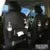 Black PU leather car seat back storage organiser with multiple pockets, attached behind a car headrest.