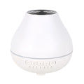 White round Bluetooth aroma diffuser with night light on wooden table, showing mist outlet and water tank.