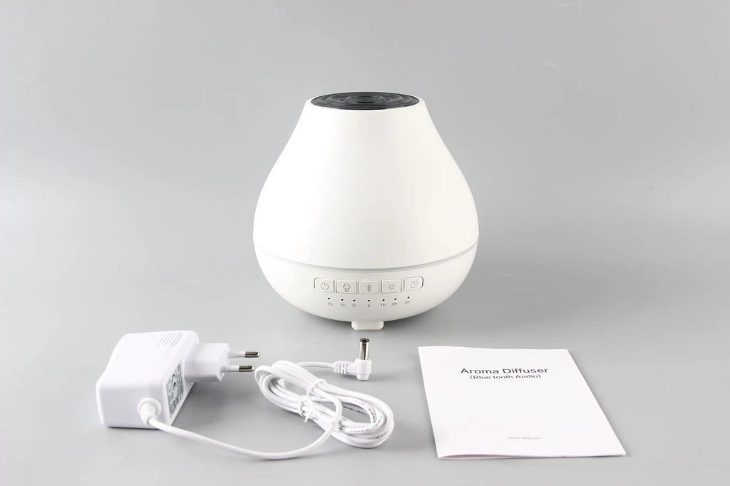 White round Bluetooth aroma diffuser with night light on wooden table, showing mist outlet and water tank.