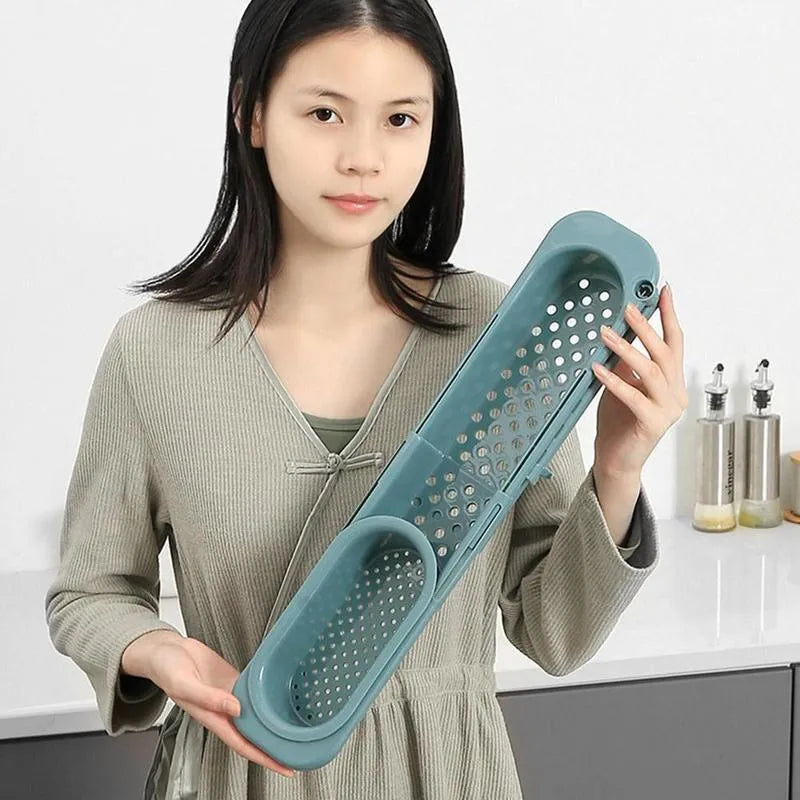 Blue grey adjustable telescopic sink rack organiser with drainer basket holding a sponge and soap bottle.