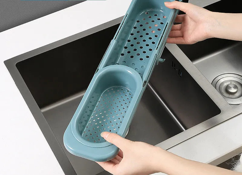 Blue grey adjustable telescopic sink rack organiser with drainer basket holding a sponge and soap bottle.