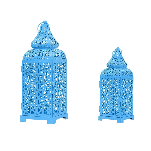Blue iron geometric Moroccan candelabra holding a lit candle, with spare yellow and white taper candles beside it.