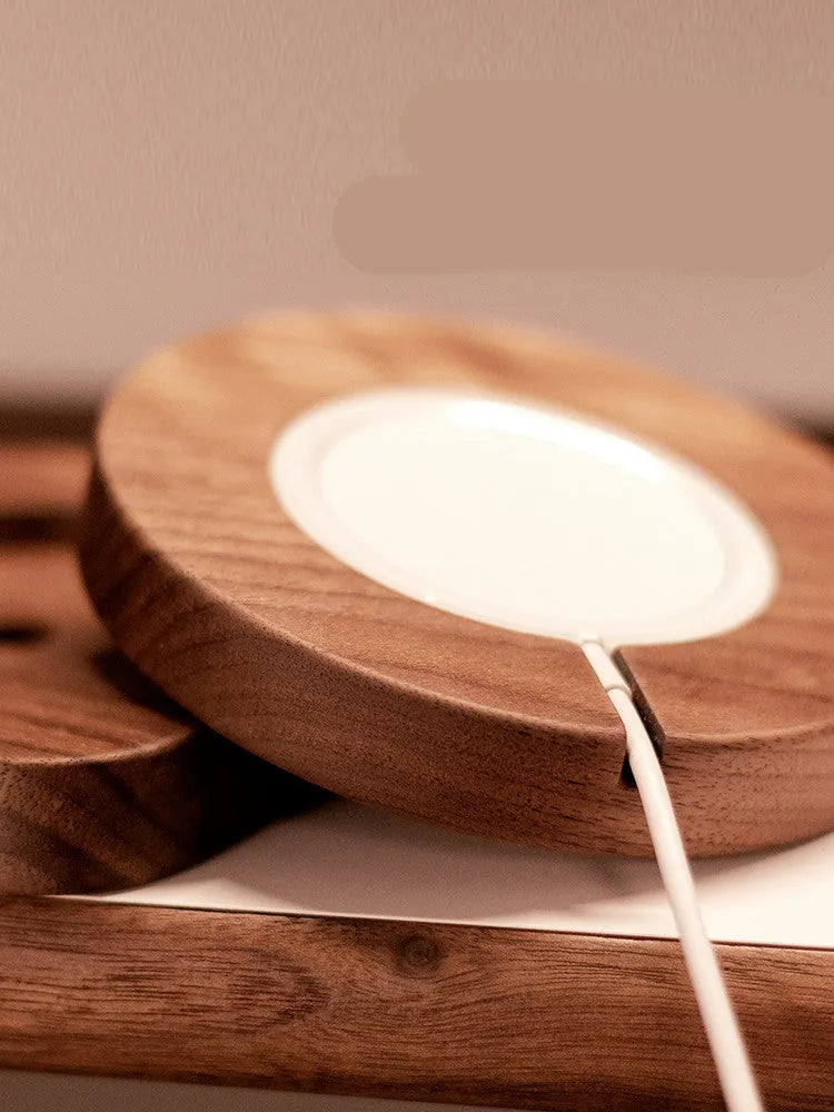 Walnut wood magnetic wireless charging bracket for desktop with phone protective cover.