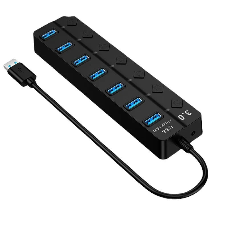 Black 7-port USB 3.0 hub with external power adapter and individual switches for each port on a desk.