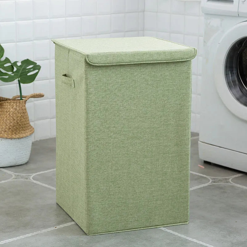 Washable fabric laundry sorting box in beige, shown next to a small pile of towels.