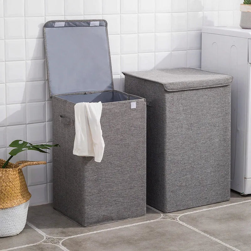 Washable fabric laundry sorting box in beige, shown next to a small pile of towels.