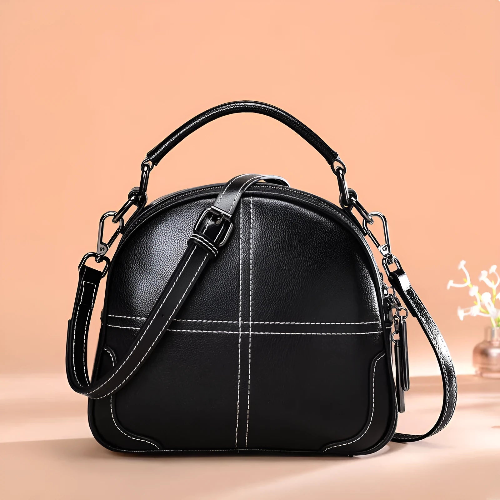 Round leather handbag with a zipper opening and a soft handle in a wine red colour.