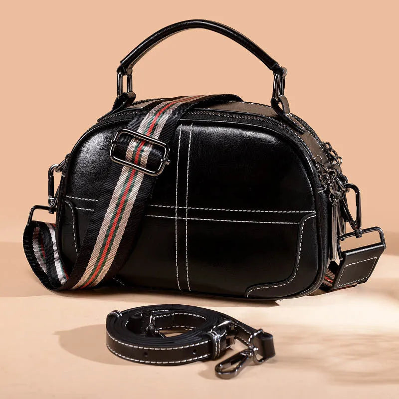 Round leather handbag with a zipper opening and a soft handle in a wine red colour.