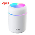 Pink USB desktop humidifier with coloured LED lights and water tank on a wooden desk.