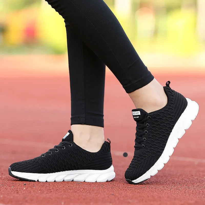 Women's running shoes in black, pink, or white with a mesh upper and rubber outsole.