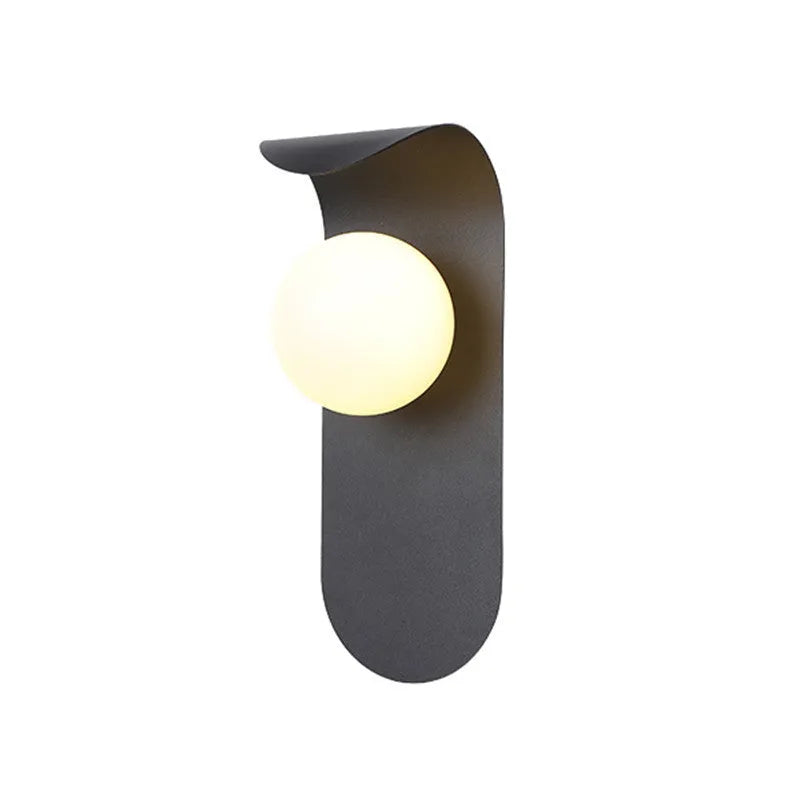 Modern minimalist wall lamp in black finish with LED warm light on a bedroom wall beside bed