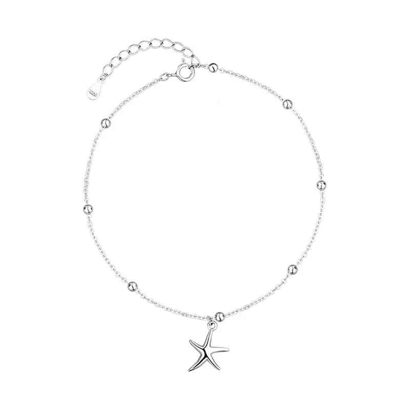 Close-up of a sterling silver anklet with round beads, a starfish charm, and an extender chain on an ankle.