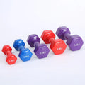 Set of bright coloured plastic fitness dumbbells in different weights on a floor.