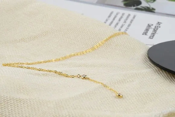Gold alloy snake bone chain necklace with geometric pendant on display