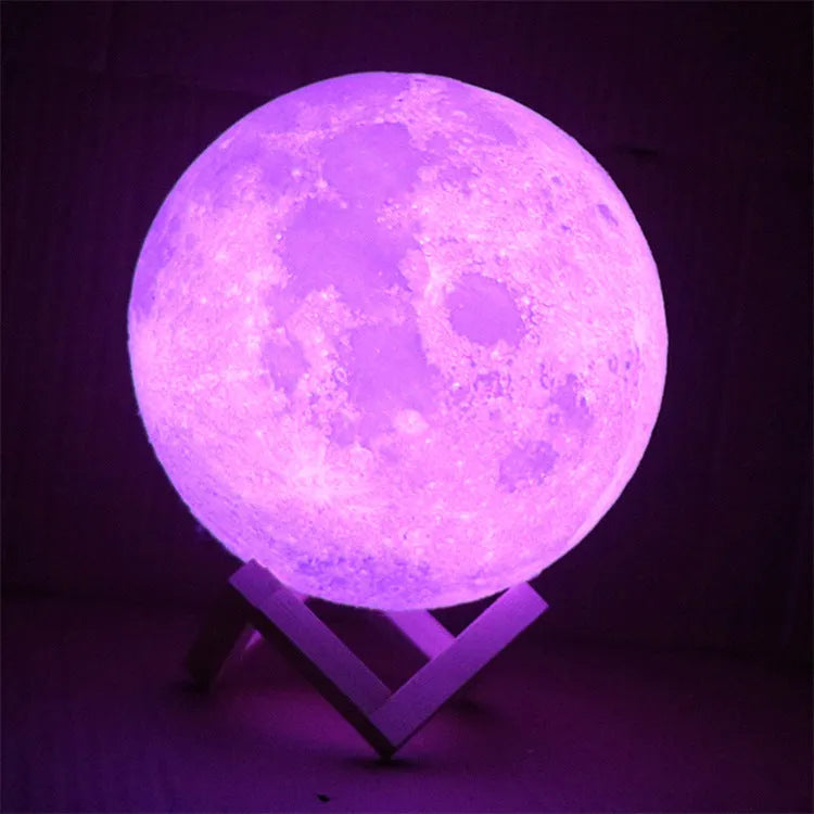 3D printed white moon lamp on a wooden holder, showing detailed lunar surface and a glowing yellow light.