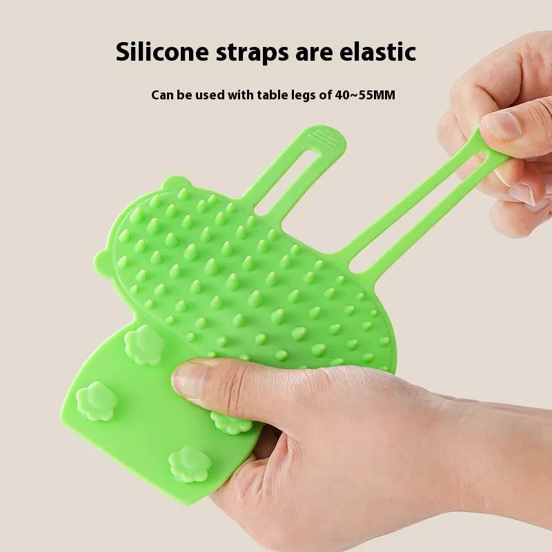 Silicone cat grooming comb with adjustable strap mounted on a furniture leg