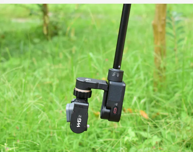 Black retractable selfie stick with extended aluminium pole and Bluetooth remote, holding a smartphone.