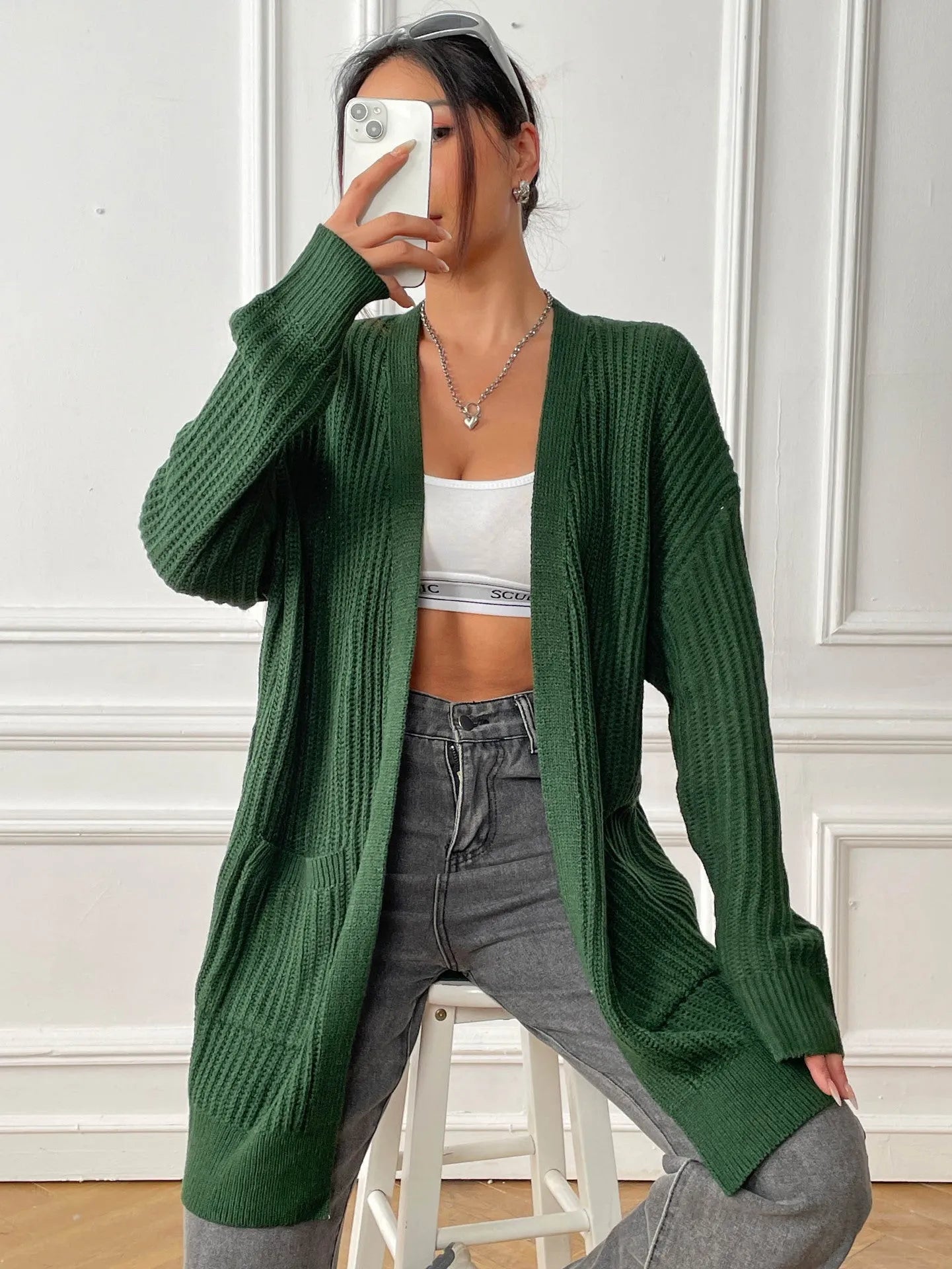 Dark green loose women's cardigan with two pockets and long sleeves.