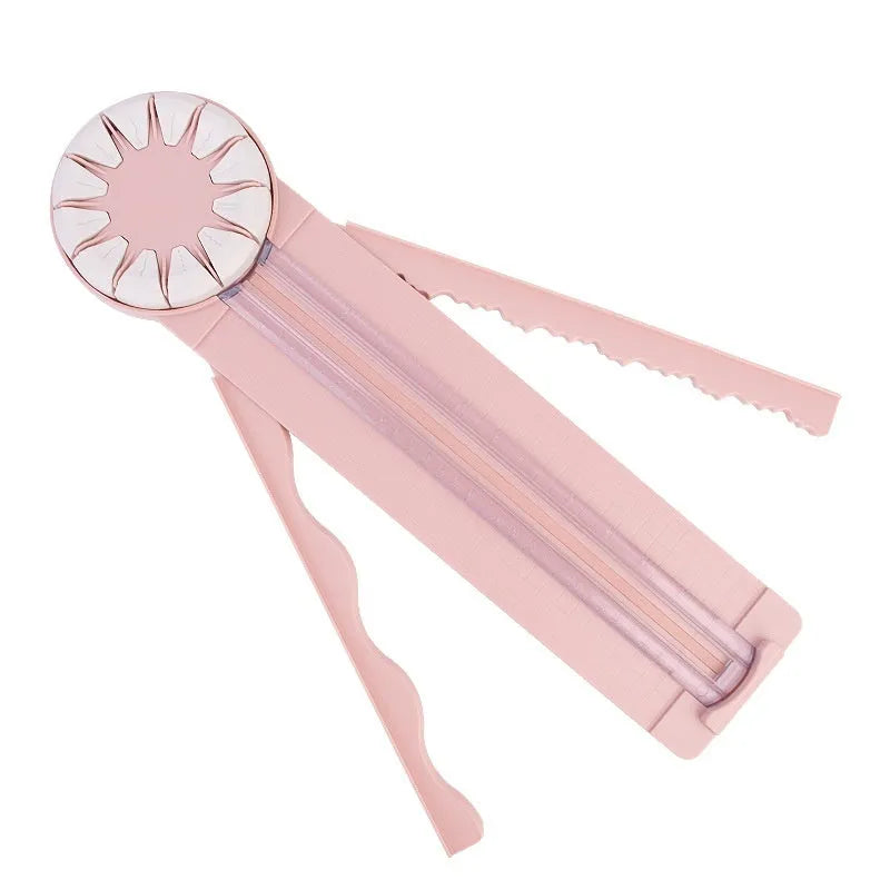 Pink and black 12-in-1 dotted line plastic rotary paper cutting machine on a craft table.