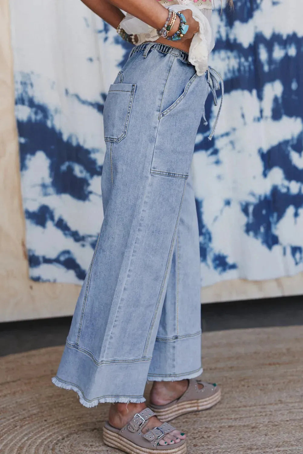Beau blue women's wide-leg denim trousers with a drawstring waistband and raw hem detail.