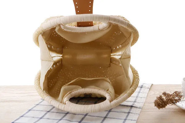 Women's round woven paper rope handbag in beige with hard shell, cover closure, and hard handle