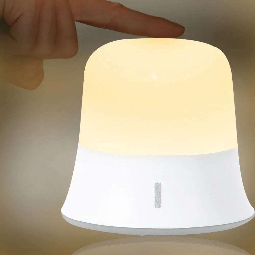 White cylindrical touch control bedside night light with USB charging cable.