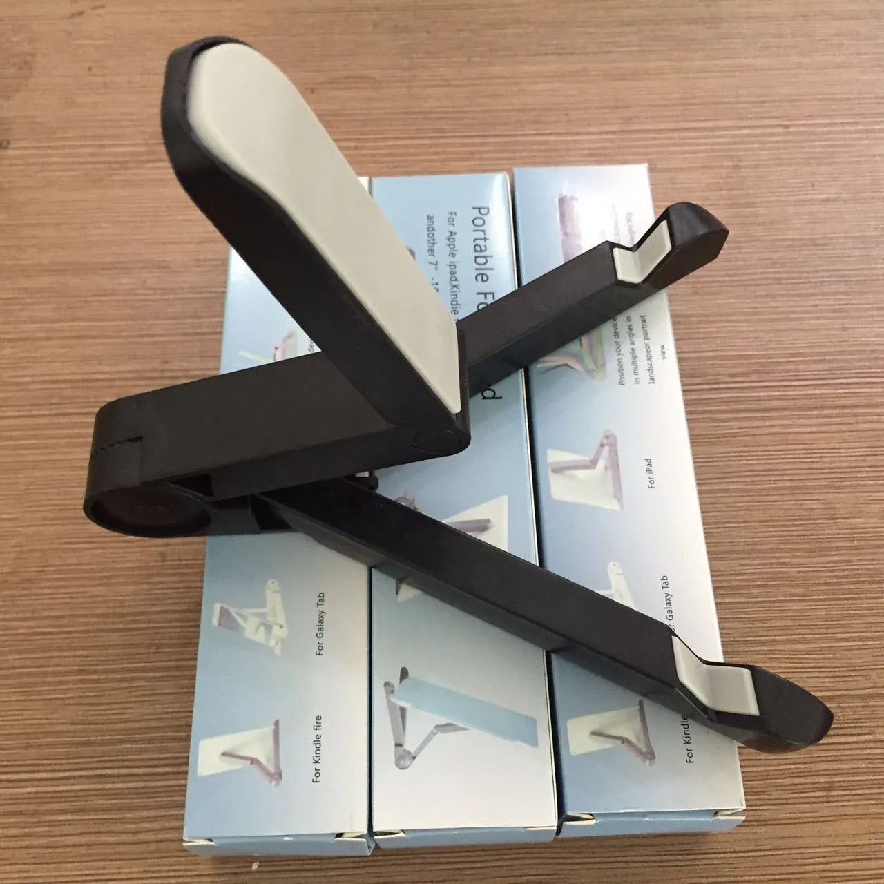 Black foldable tablet holder displaying smartphone in landscape position on desk
