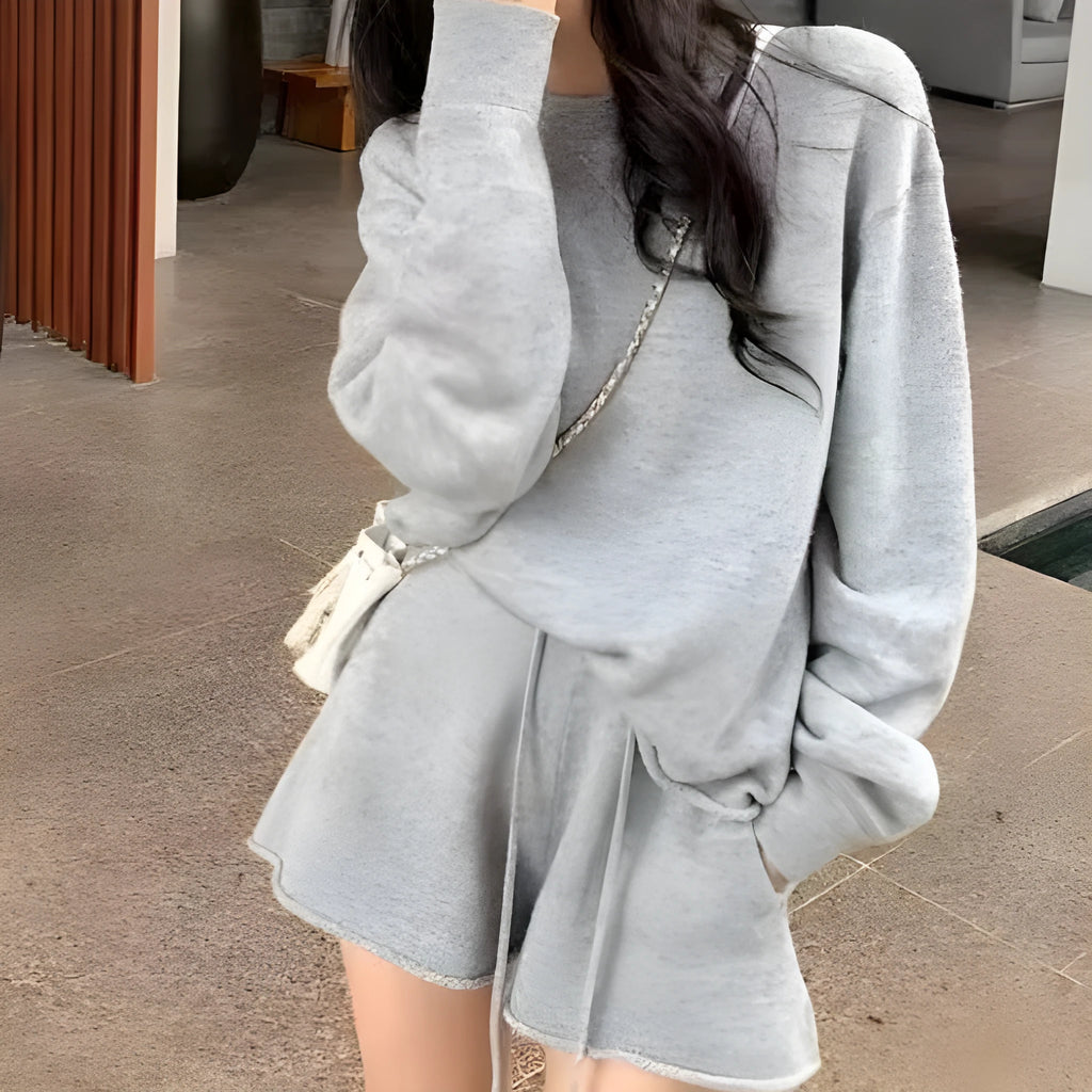 Woman wearing a loose-fit long sleeve knitted sweater and matching high-waisted wide-leg shorts in a neutral colour.