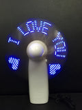 White handheld mini fan with LED lights displaying a love heart pattern, shown next to AAA batteries for scale.