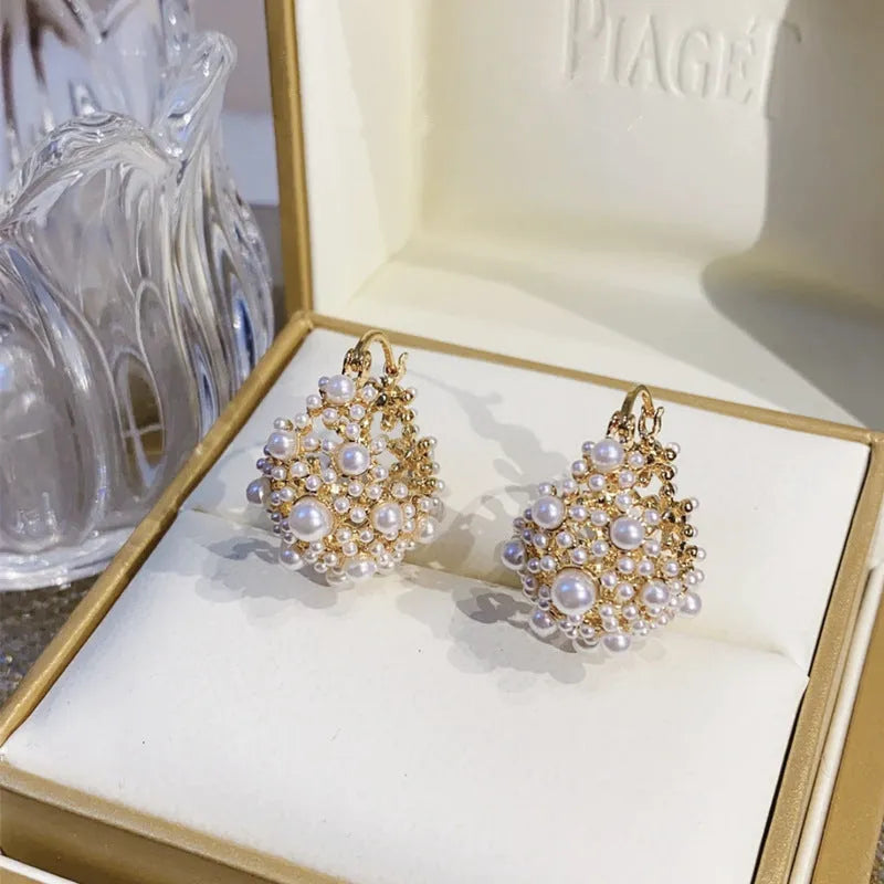 A pair of gold-coloured copper flower basket earrings with pearl inlay and small rice-shaped bead details.
