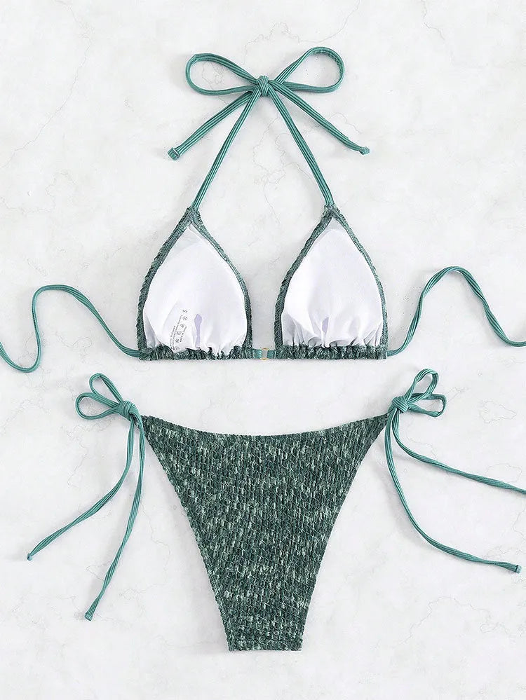 Green backless women's bikini with halter neck strap lying flat.