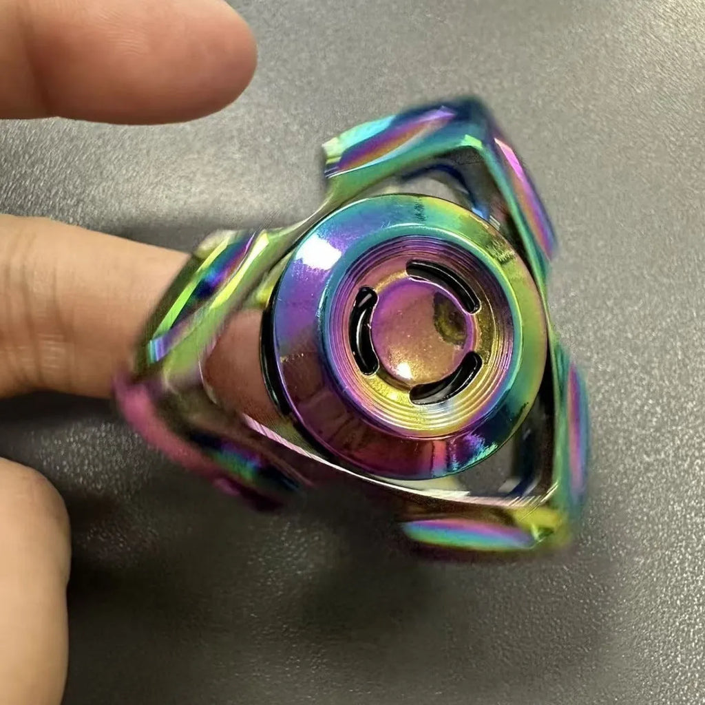 Silver and colourful alloy fingertip gyro decompression fidget toy on a plain background.