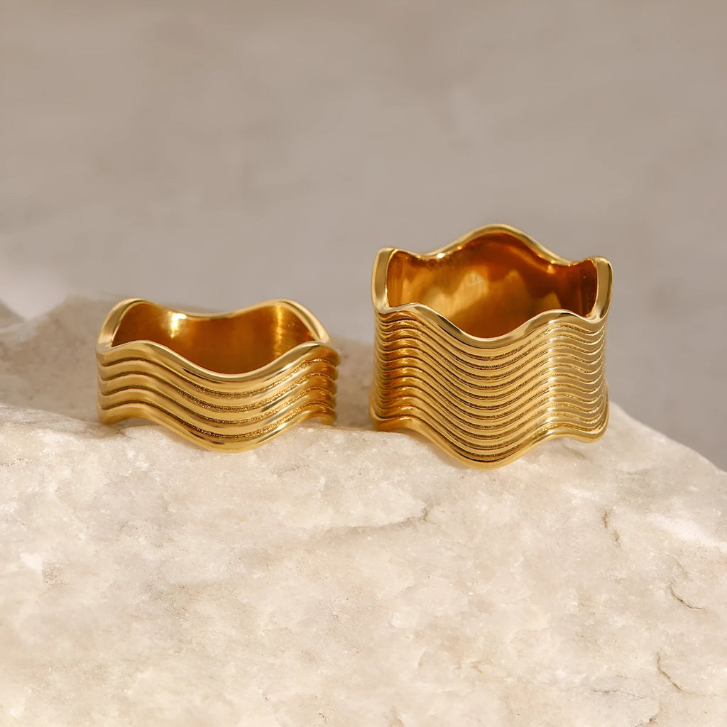 Geometric stainless steel ring with wide band and wave pattern design.