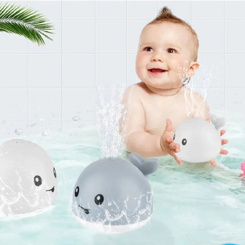 White and blue whale bath toy spraying water with LED lights on, floating in a bathtub