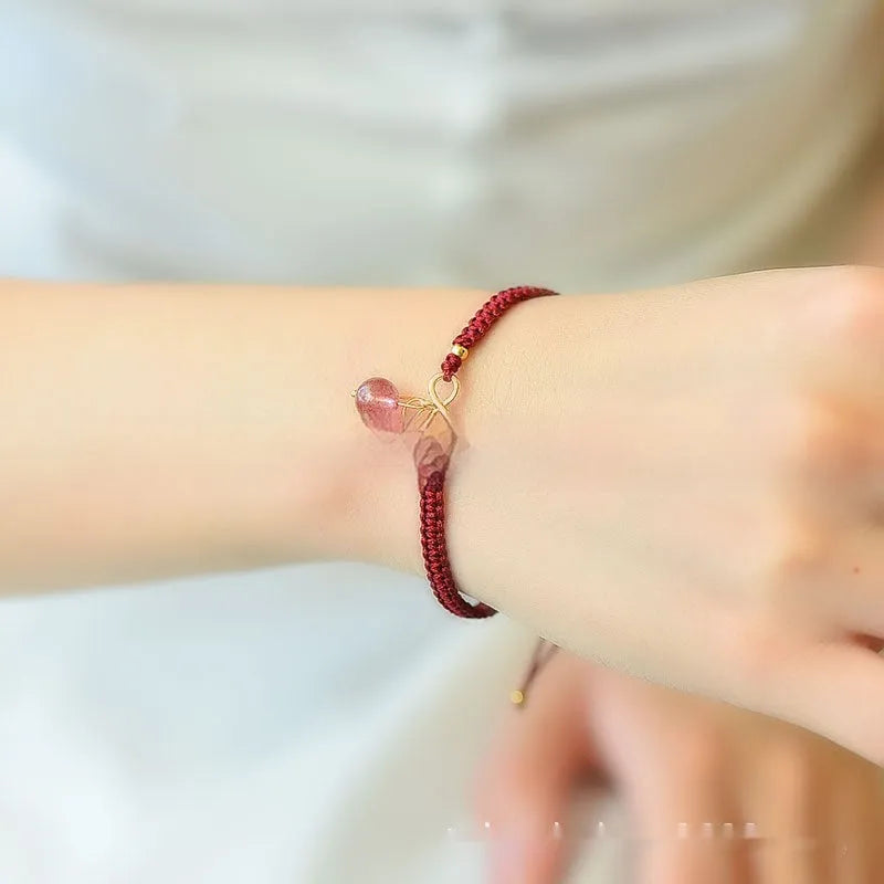Close-up of a women's strawberry quartz bracelet with red cherry-shaped beads on a stretch cord.