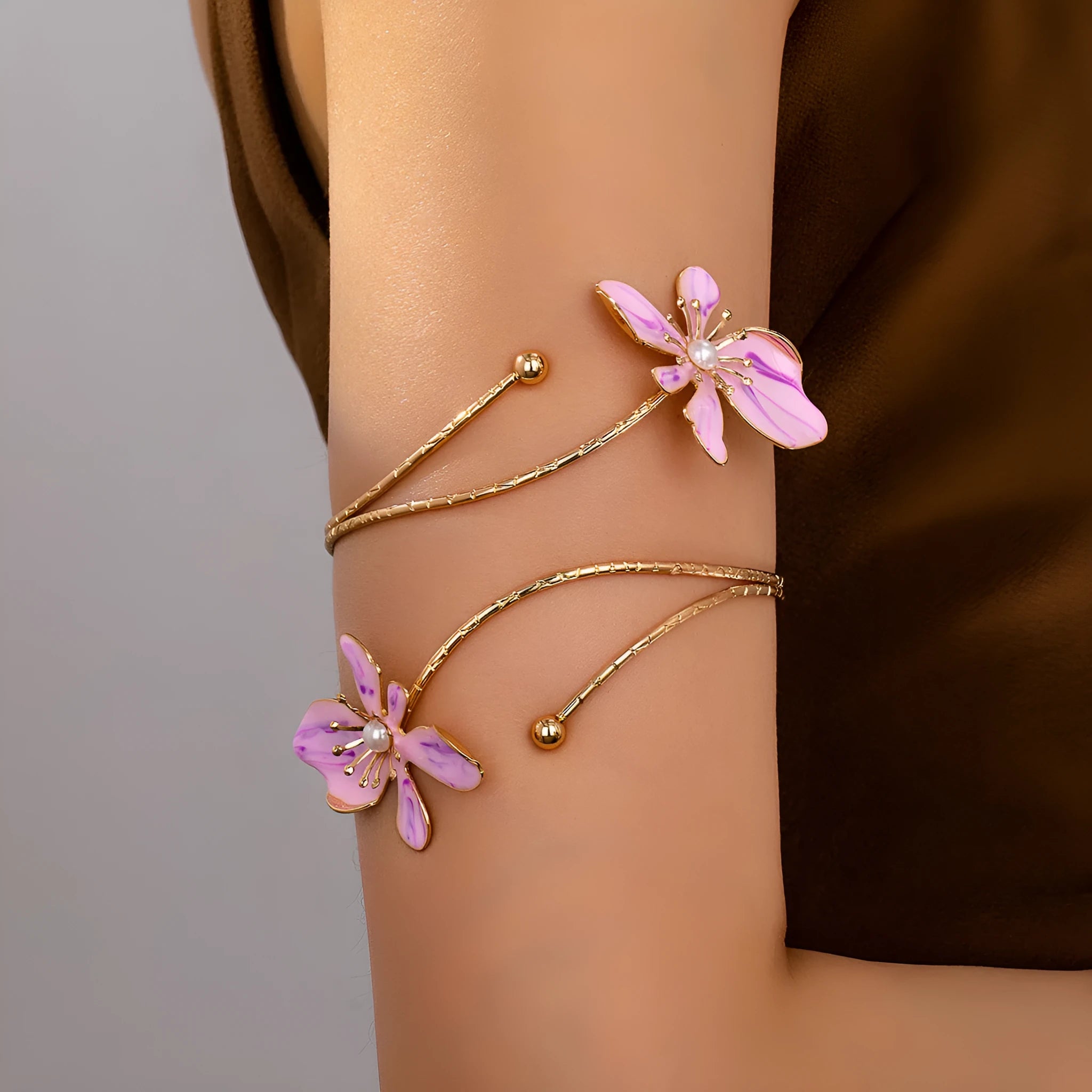 Pink hollow metal bangle with engraved pattern on a wrist, showing its open design and lightweight profile.