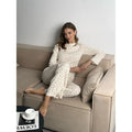 White women's floral print bell sleeve top and wide leg pants suit laid flat.