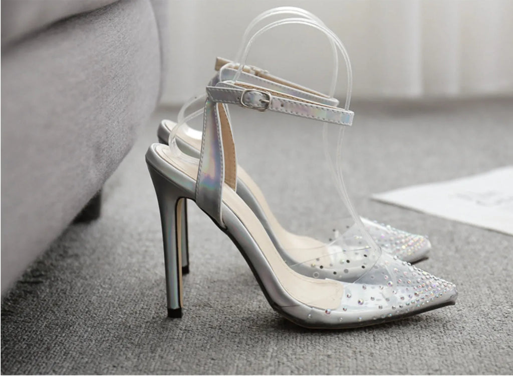 Women's pointed-toe sandals with glossy PVC upper and a thin stiletto heel on a neutral background.
