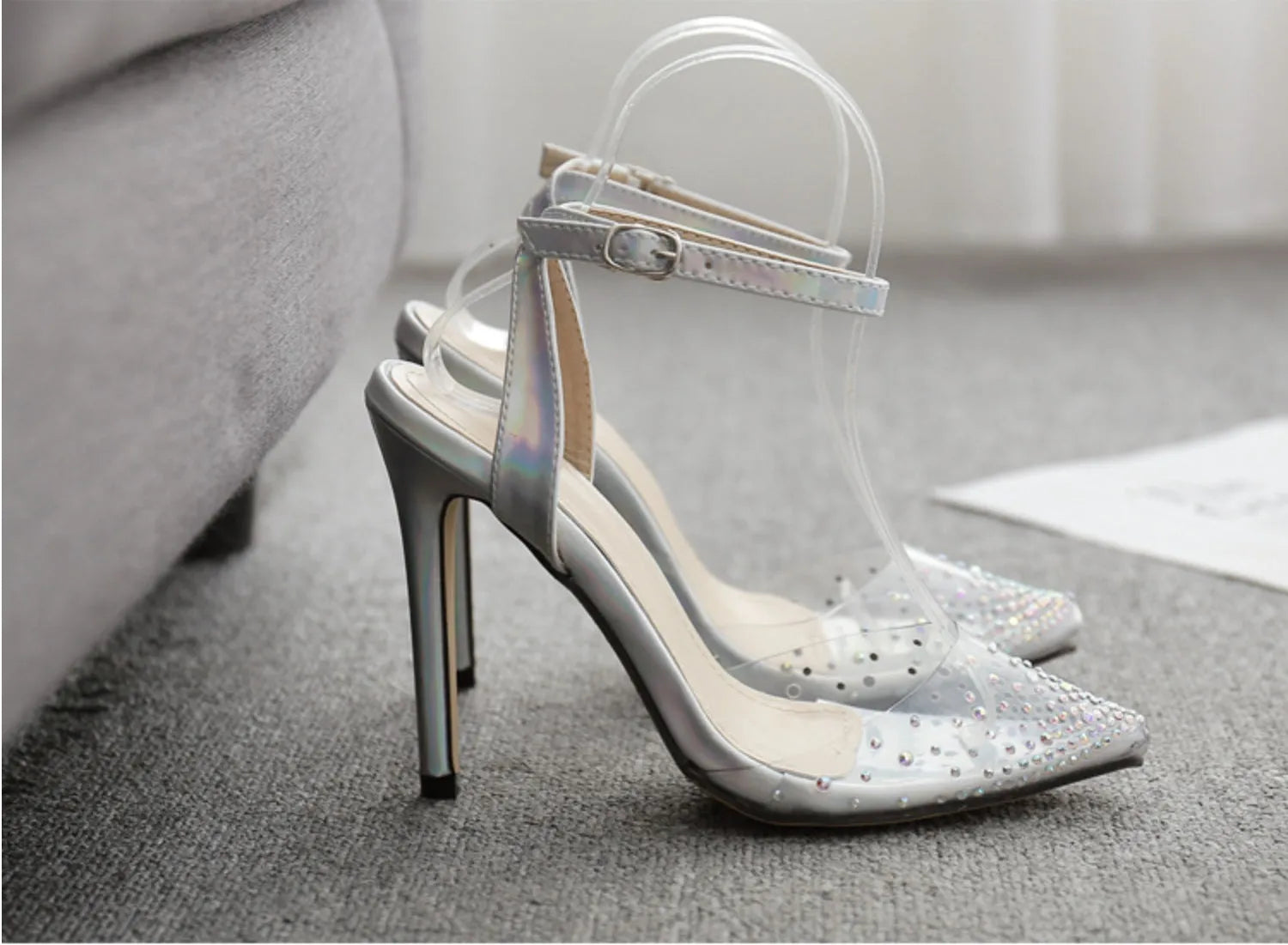 Women's pointed-toe sandals with glossy PVC upper and a thin stiletto heel on a neutral background.