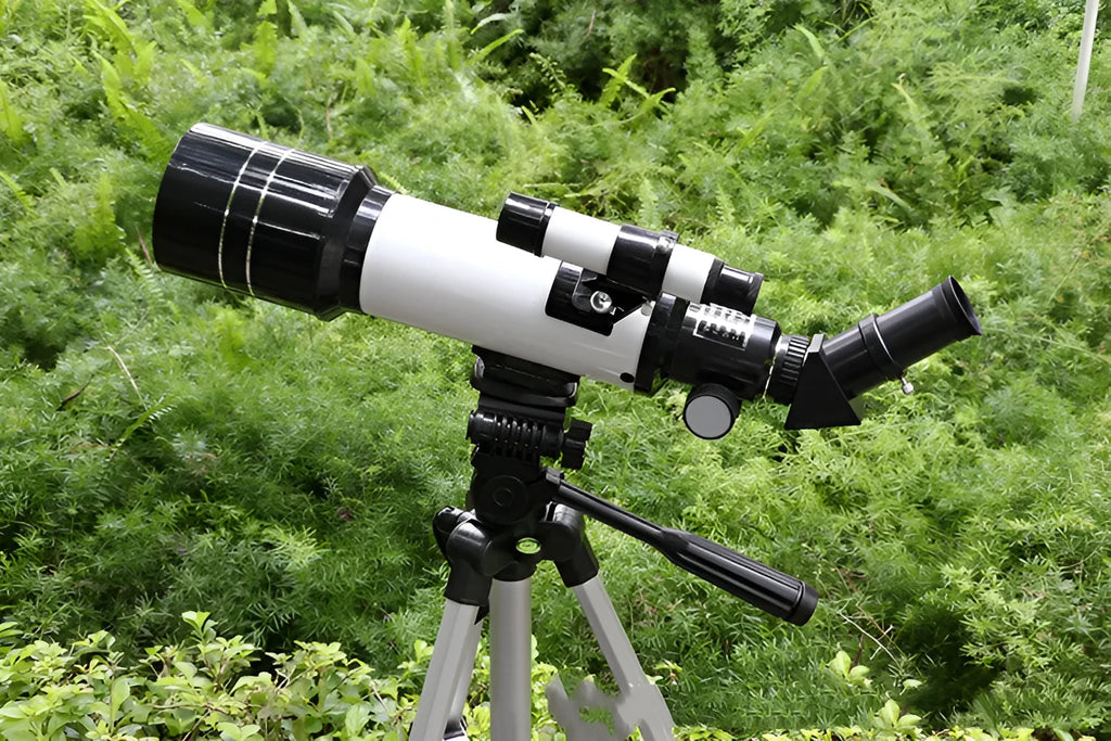 Dark blue children's astronomical telescope with adjustable magnification on a tripod, next to a mobile phone holder accessory.