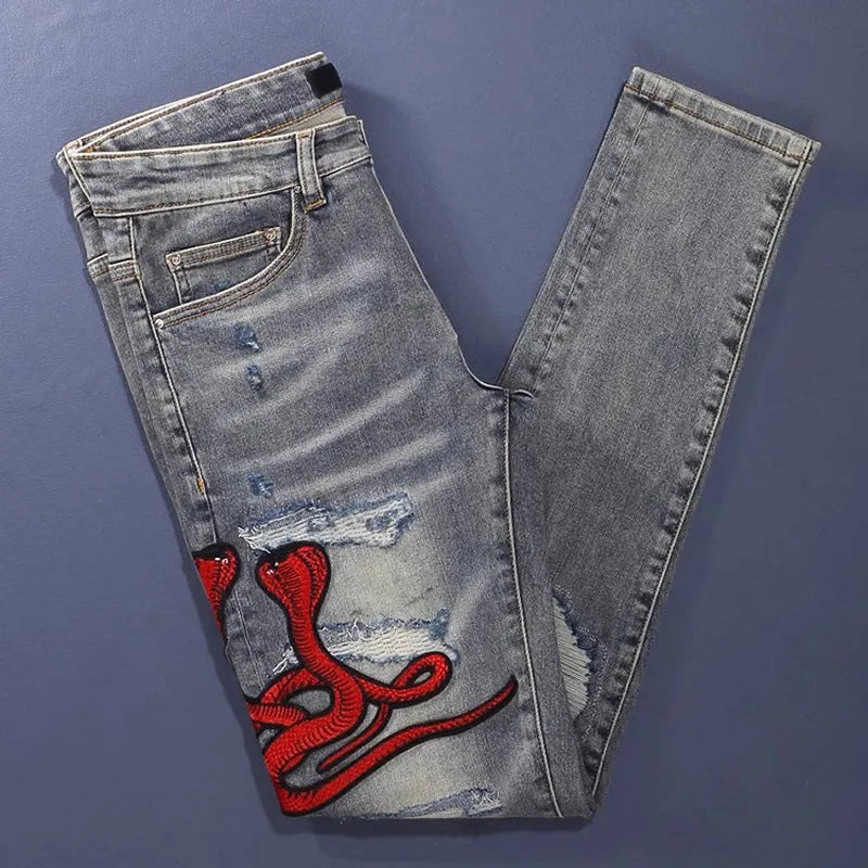 Men's slim fit washed-out denim jeans with hole patches and embroidery on a mid waist.