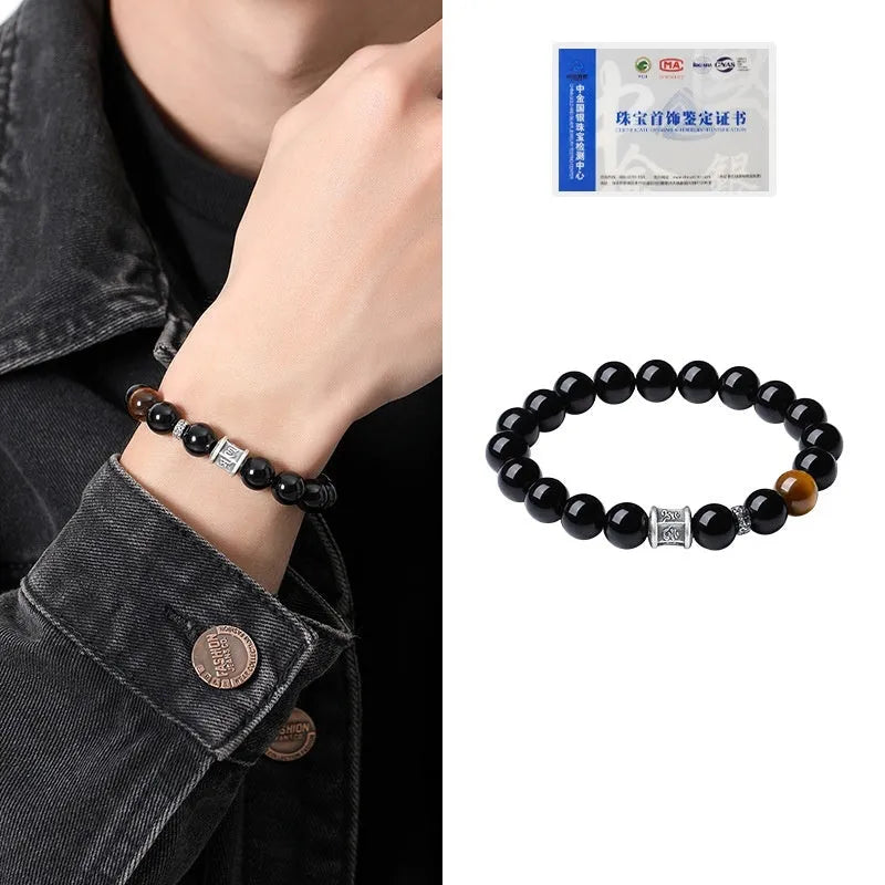Black obsidian prayer wheel bracelet for men with a hand-woven silver clasp on a wrist.