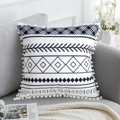 Bohemian style decorative throw pillow with polyester cover in light grey on a sofa.