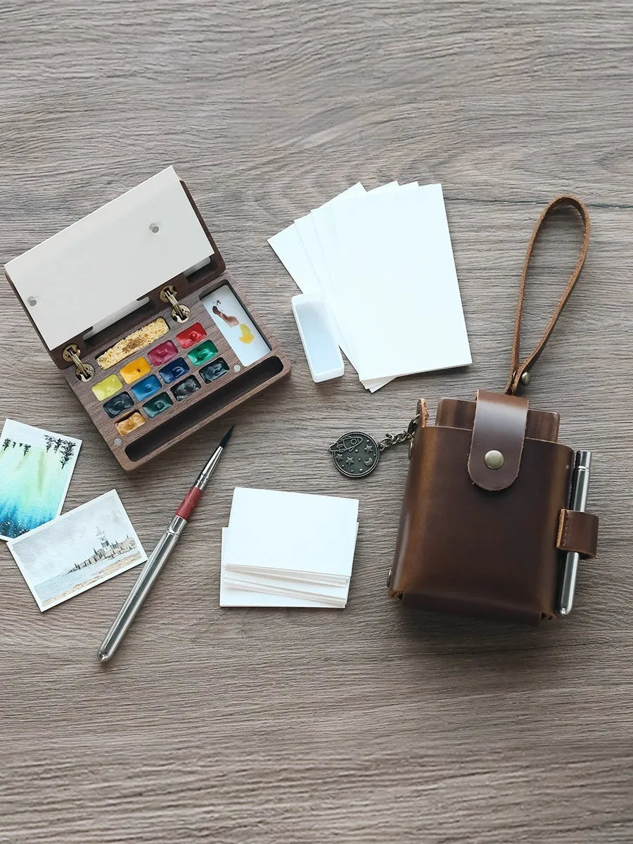 Mini wooden watercolour paint box with walnut finish, open to show pigment suit selection.