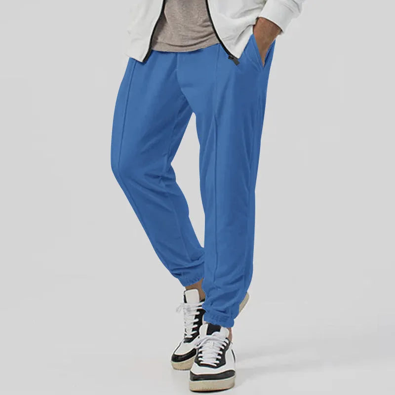 Man wearing grey loose tapered track sweatpants with a micro-elastic cotton blend fabric.